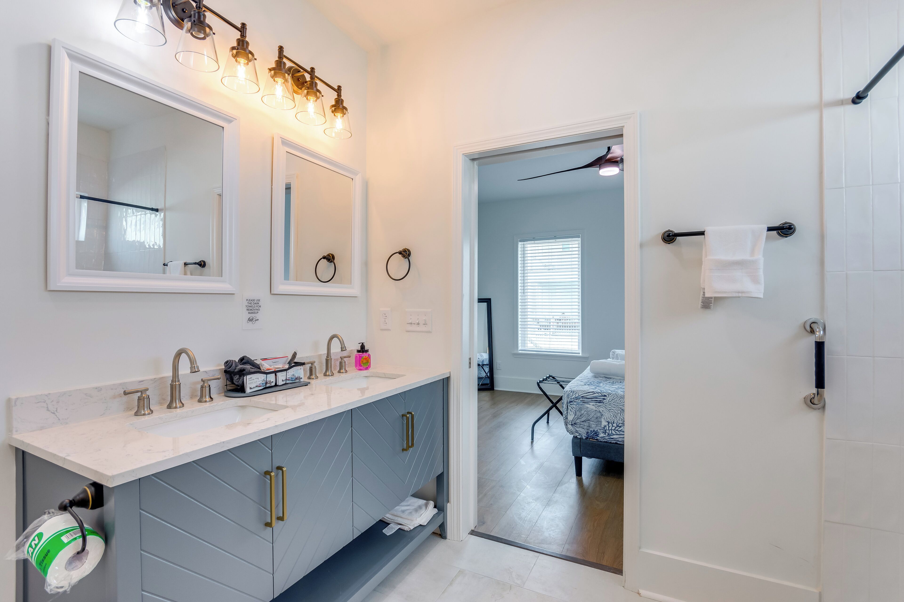 A modern bathroom with a large mirror, dual sinks, and a vanity with storage.