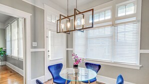 A dining area with a round glass table, blue chairs, a modern pendant light, and a vase with flowers. - 1 Mi to Dtwn: Welcoming Macon Home w/ Yard (Macon)