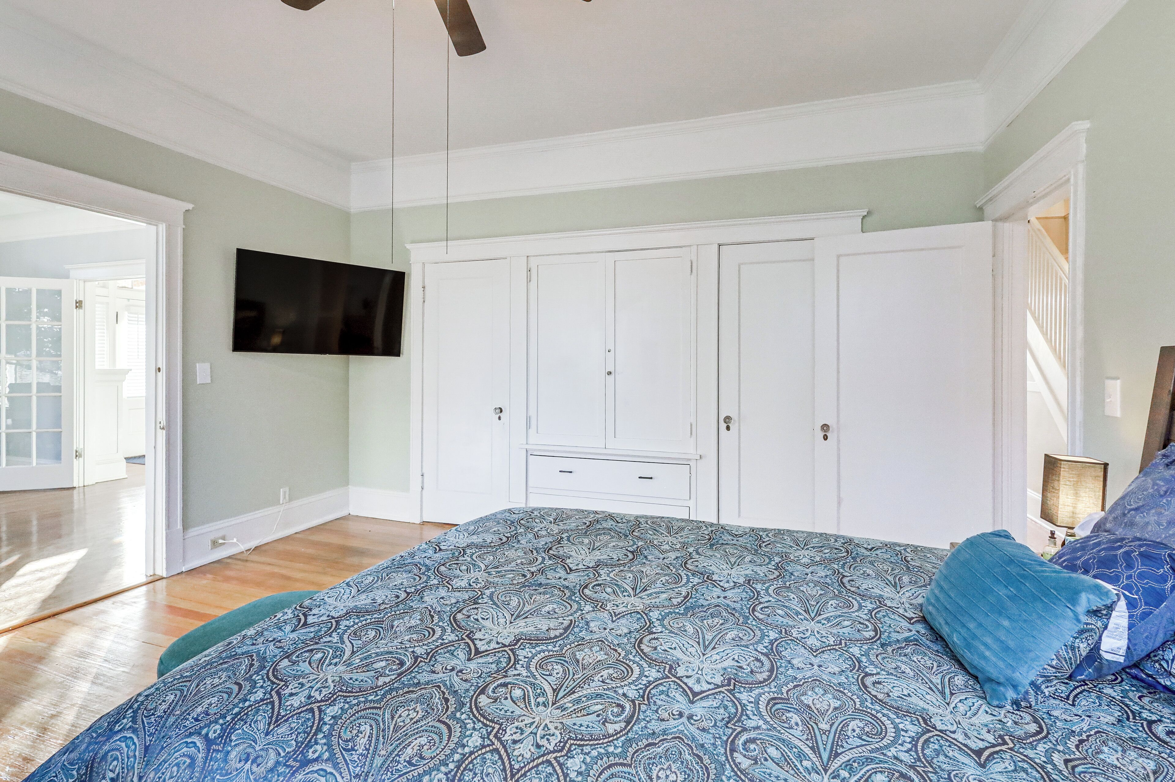 Ein Schlafzimmer mit einem großen Bett, einem an der Wand montierten Fernseher und einem Kleiderschrank.
