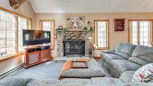 A living room with a stone fireplace, a mounted deer head, a television, and a gray sofa. - Access to Jack Frost Ski Resort: Home w/ Hot Tub (White Haven)