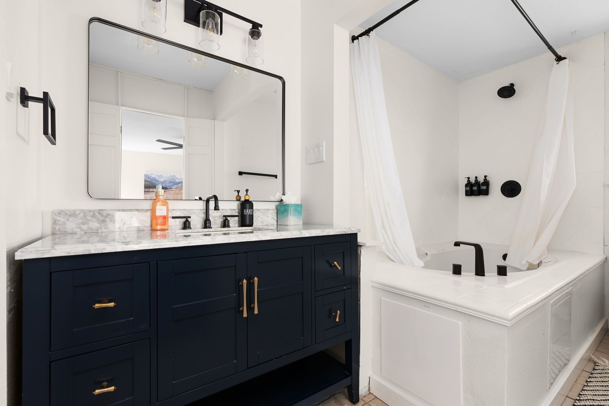 A modern bathroom with a dark vanity, a large mirror, and a separate shower area with a curtain.