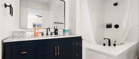 A modern bathroom with a dark vanity, a large mirror, and a separate shower area with a curtain.