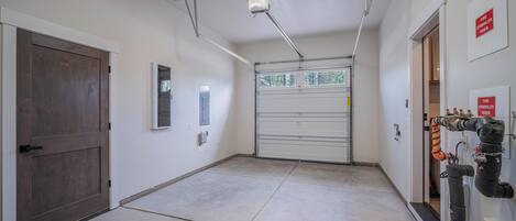 A clean, well-lit hallway with a garage door, a fire sprinkler system, and a wooden door.