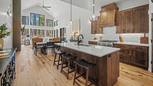 Une cuisine moderne dotée d’un grand îlot central, de meubles en bois et d’un coin repas avec des tabourets de bar.