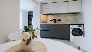 Una cocina moderna con armarios grises, lavadora integrada y cafetera.