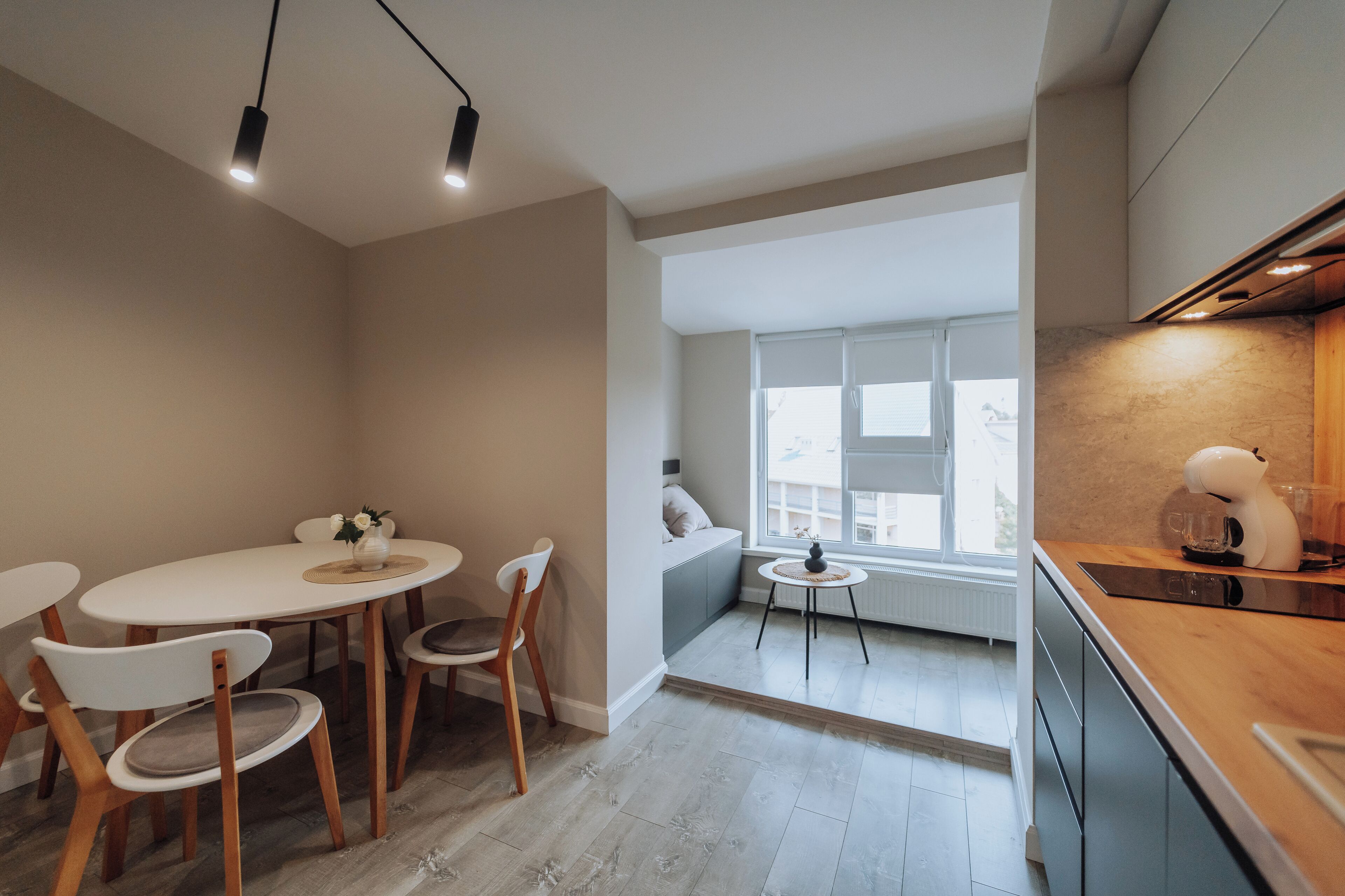 A modern kitchen with a dining area, a built-in oven, and a view to a balcony.