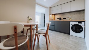 Una cocina moderna con lavadora y secadora integradas, sillas de madera y una mesa de comedor con un florero.