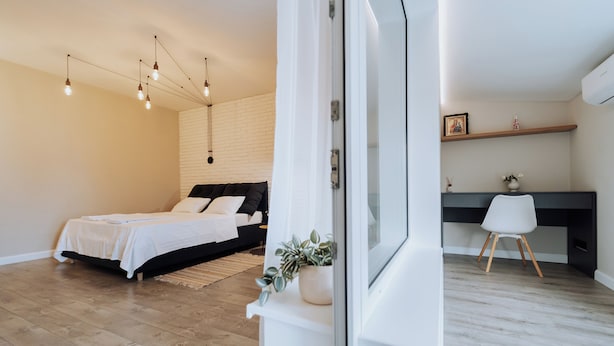Un dormitorio moderno con cama, mesita de noche y una planta en maceta.