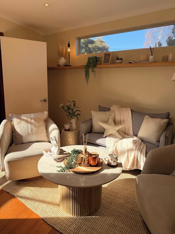A modern living room with a sofa, armchairs, a coffee table, and a bookshelf.