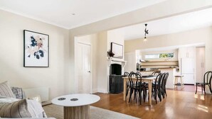 A spacious living area with a dining table, chairs, a fireplace, and a kitchen in the background.
