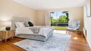 A bedroom with a bed, bedside table, chair, and a view of the outdoors.