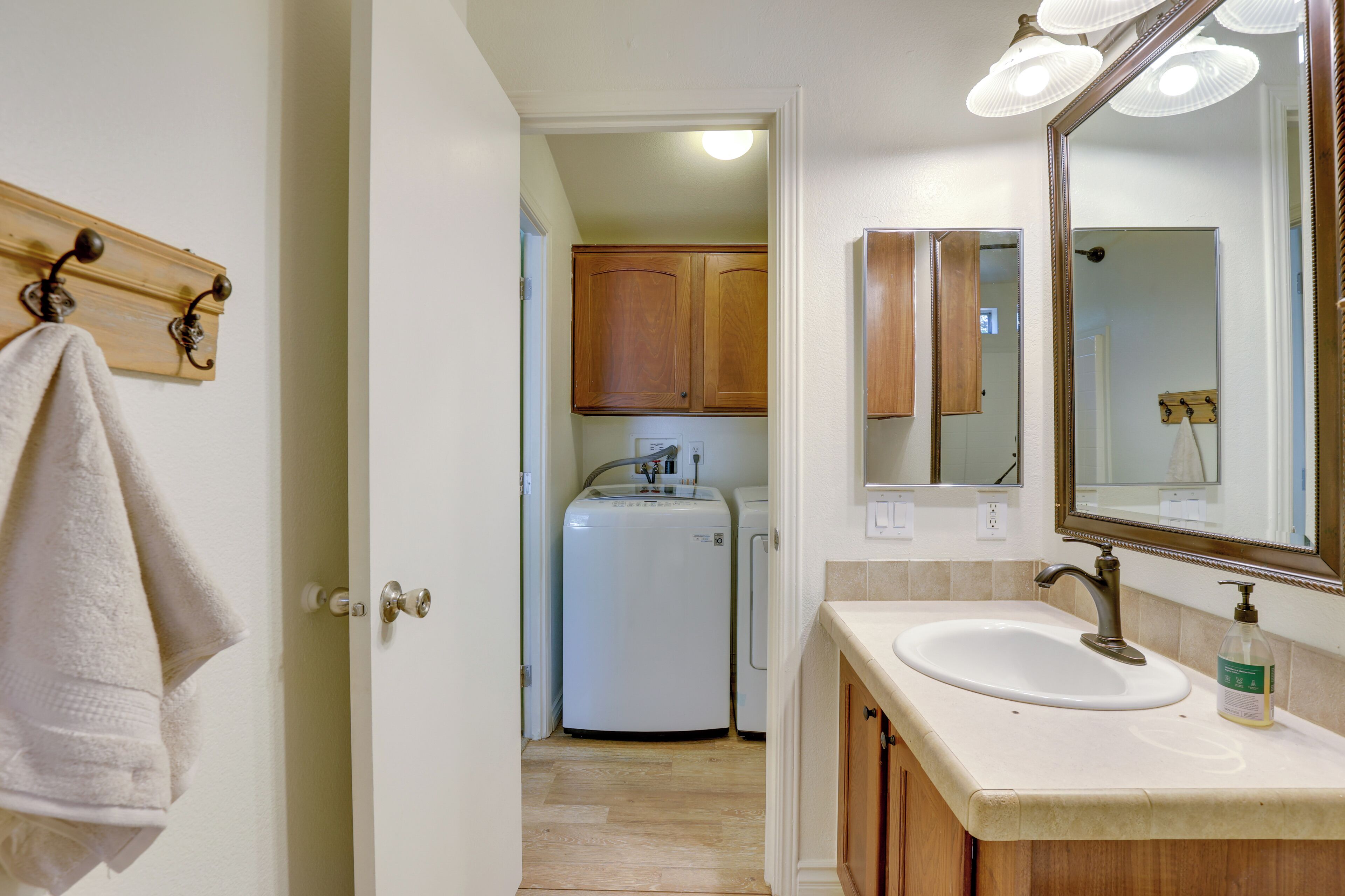 A bathroom with a white sink, a mirror, and wooden cabinets.