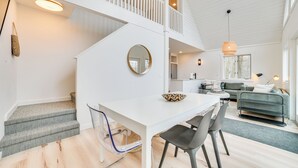 A modern interior with a white staircase, a dining area with a white table and chairs, and a living area with a sofa and a coffee table. - 2 Mi to Nubs Nob Resort: All-season Michigan Haven (Harbor Springs)
