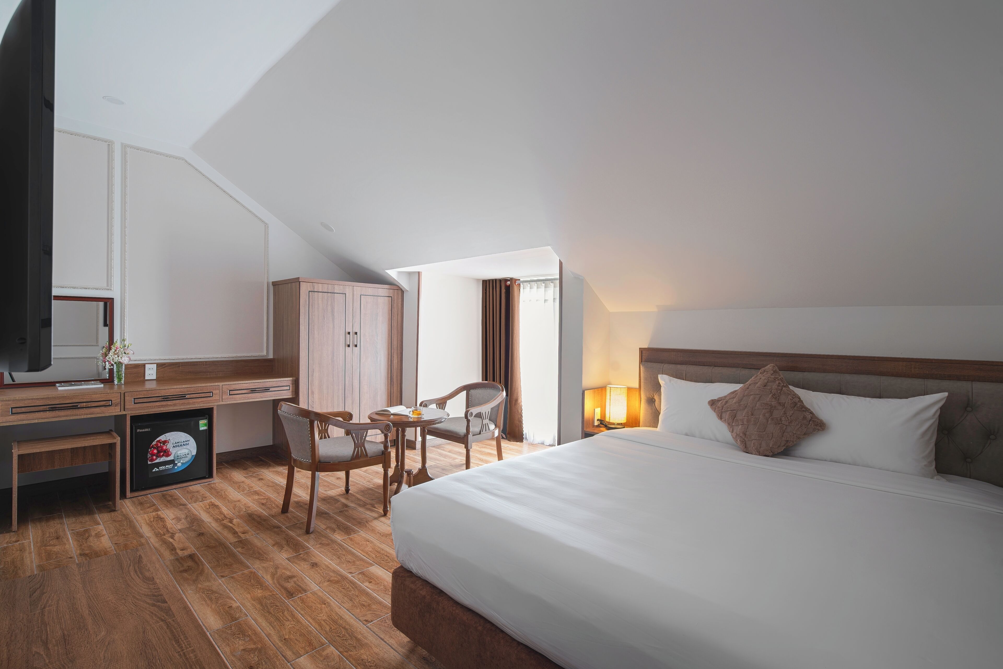 A hotel room with a large bed, a desk with a computer, a chair, and a television.
