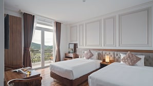 Une chambre d’hôtel avec deux lits, un bureau et une vue sur l’extérieur.