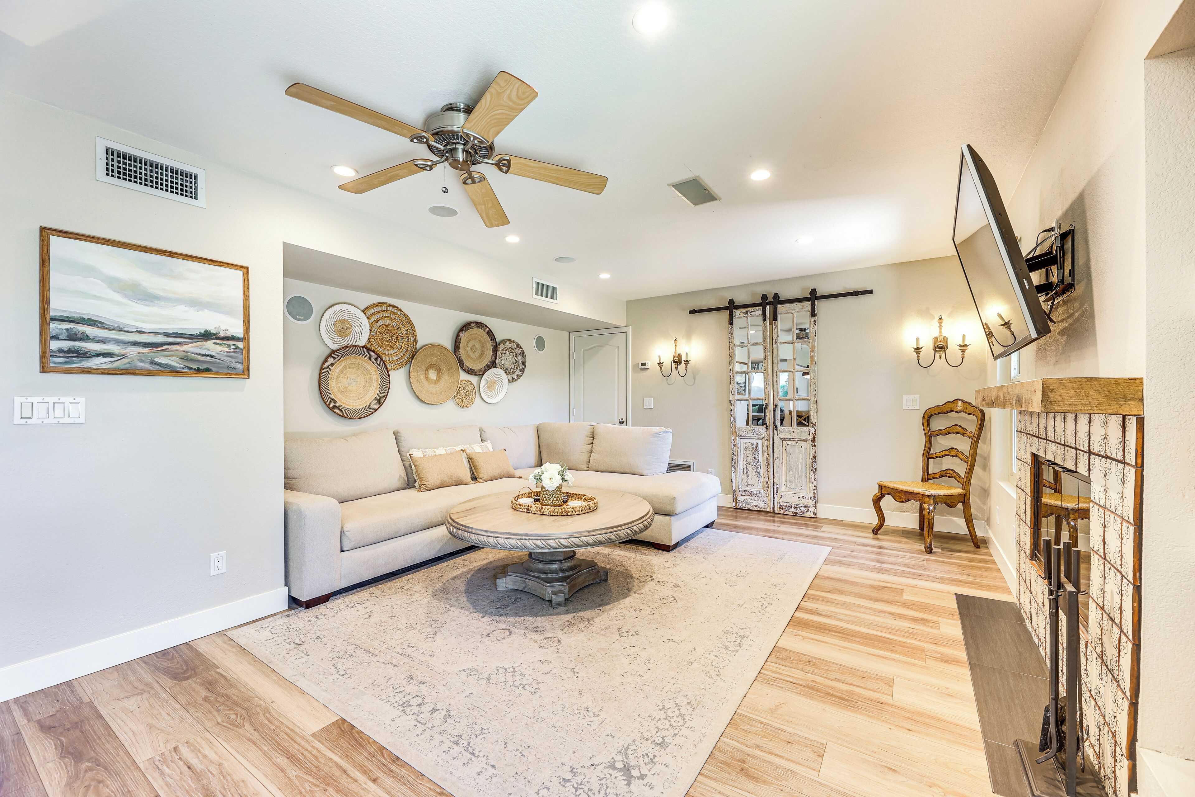 A spacious living room with a large sofa, a coffee table, and a ceiling fan.