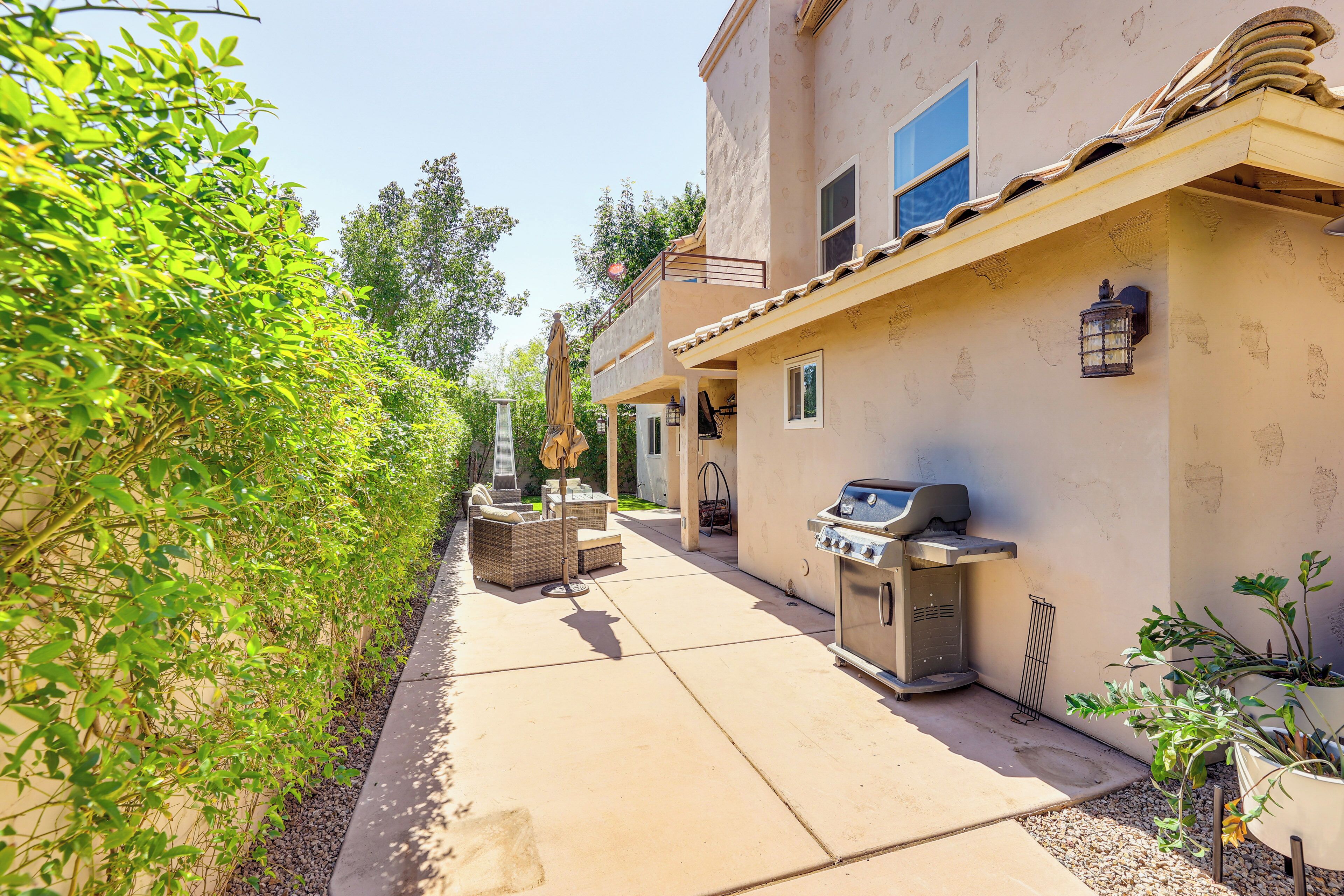 Un espace patio aménagé avec un barbecue, du mobilier d’extérieur et une lanterne fixée au mur.