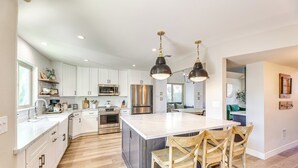 A modern kitchen with white cabinets, stainless steel appliances, and a large island with bar stools. - Val Vista Lakes Group Getaway: Lake & Pool Access! (Gilbert)