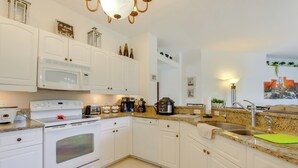 Eine Küche mit weißen Schränken, einer Mikrowelle, einem Backofen, einer Kaffeemaschine und einem Spülbecken.