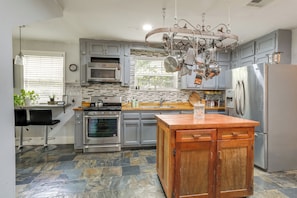 A modern kitchen with grey cabinets, a stainless steel refrigerator, and a wooden island. - 2 Mi to Lsu: Mid City Home w/ Yard & Patio! (Baton Rouge)