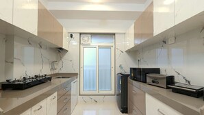 A modern kitchen with marble countertops, stainless steel appliances, and a central island. - 3BHK Master Suite (Gagal Home) (Mumbai)