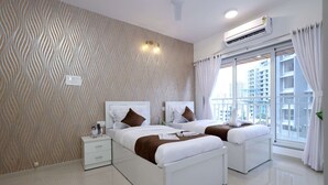 A modern hotel room with two beds, a large window with curtains, an air conditioning unit, and a patterned wall. - 3BHK Master Suite (Gagal Home) (Mumbai)