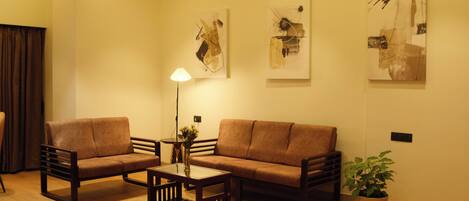 A living room with two sofas, a coffee table, a lamp, and abstract wall art.