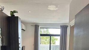 A hotel room with a bed, a desk, a washing machine, and a large window with curtains. - Comffy Cozzy Studio  Embassy Gardens, Accra (Accra)