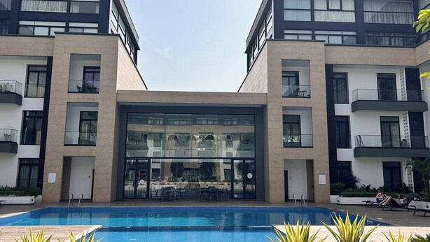 A modern building with a central glass facade, a swimming pool, and outdoor seating areas. - Comffy Cozzy Studio  Embassy Gardens, Accra (Accra)