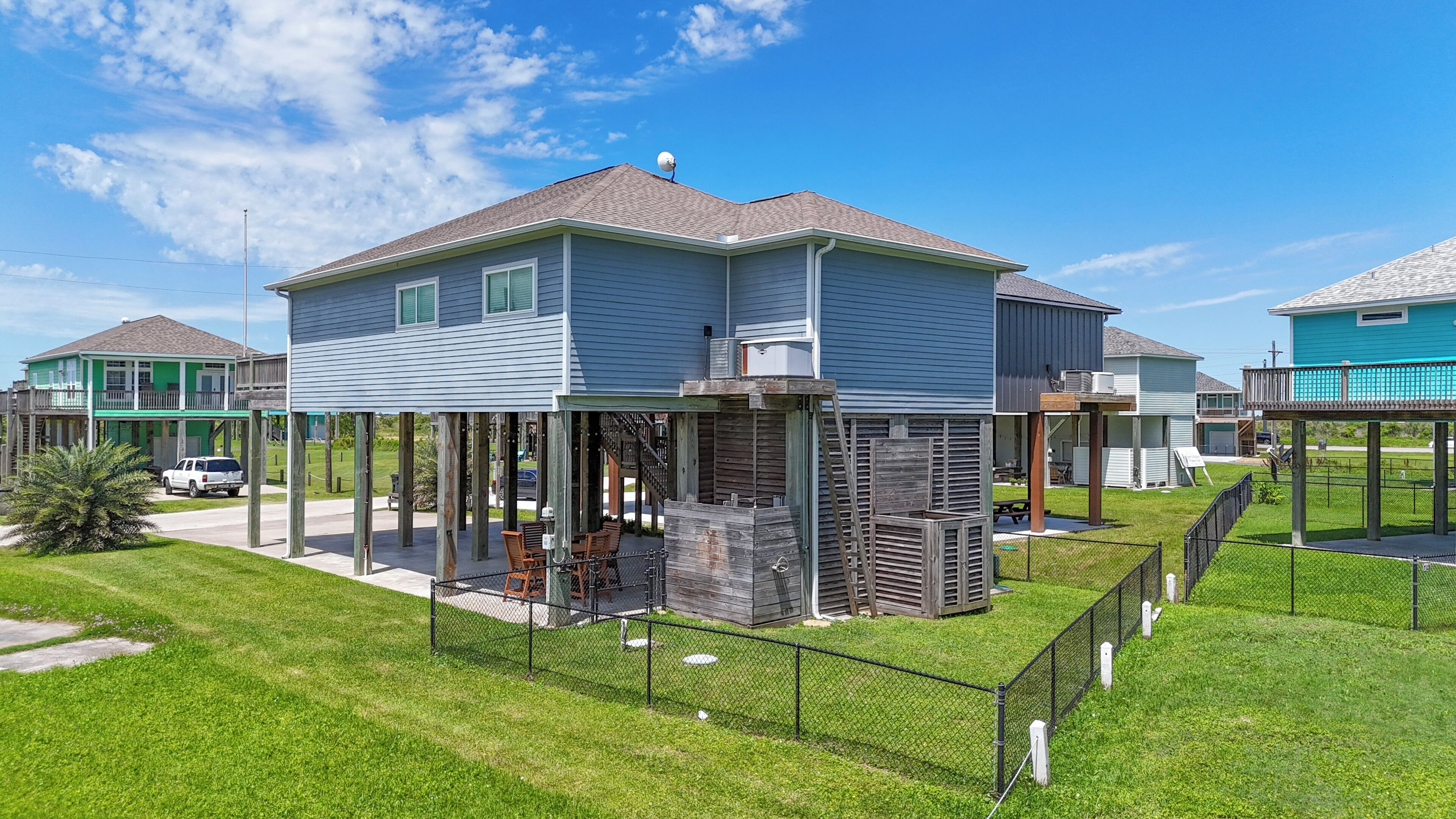 A two-story house with a covered patio, a fenced yard, and a neighboring house.