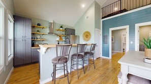 Una cocina moderna con gabinetes grises, encimeras de madera y una zona de bar con taburetes.