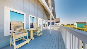 Una terraza de madera con mobiliario exterior y vista a la playa.