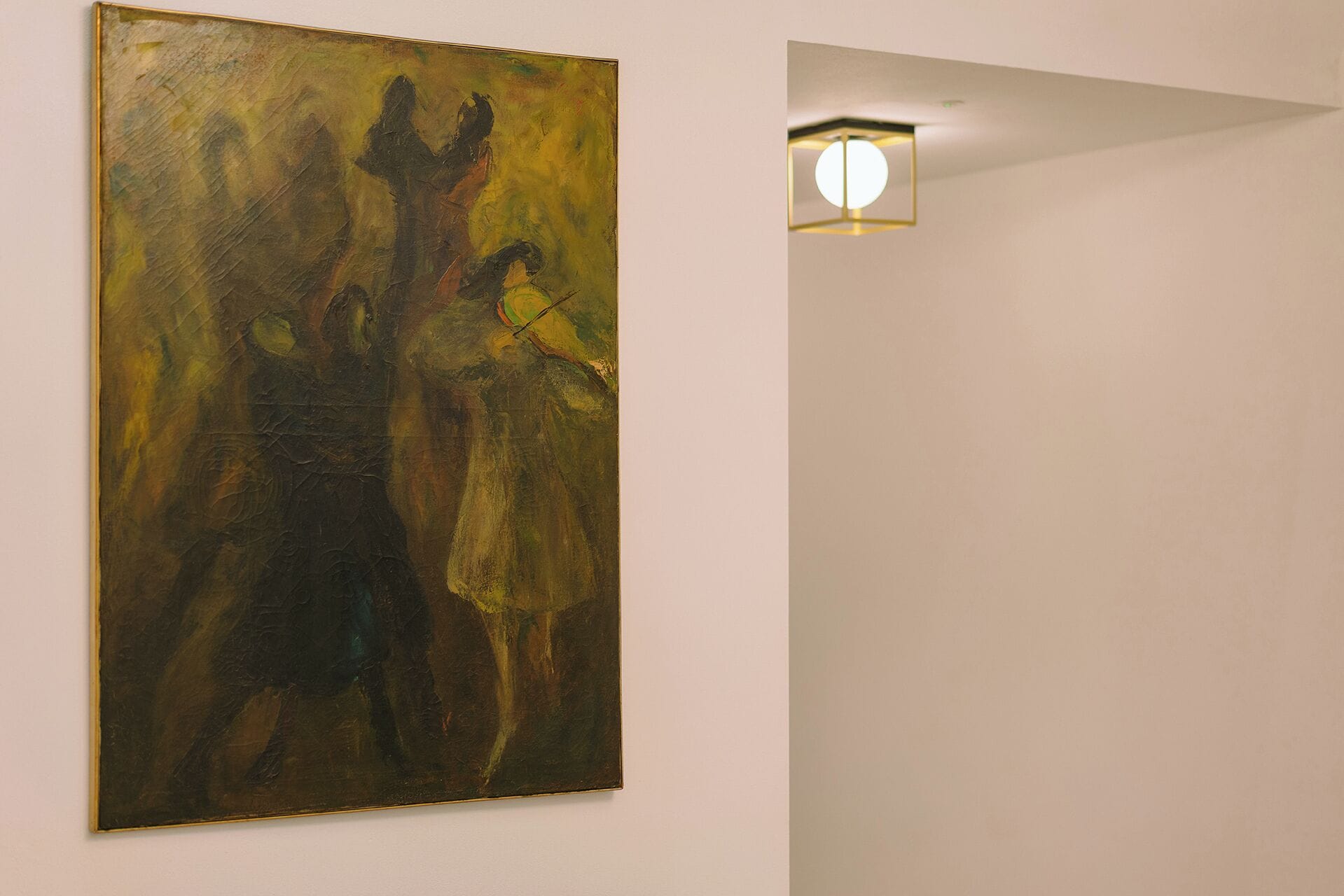 A painting on a wall in a room with a light fixture.