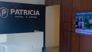 Un hall d’hôtel moderne comprenant un comptoir d’accueil, un écran de télévision diffusant les actualités et un espace détente avec un canapé et une table basse.