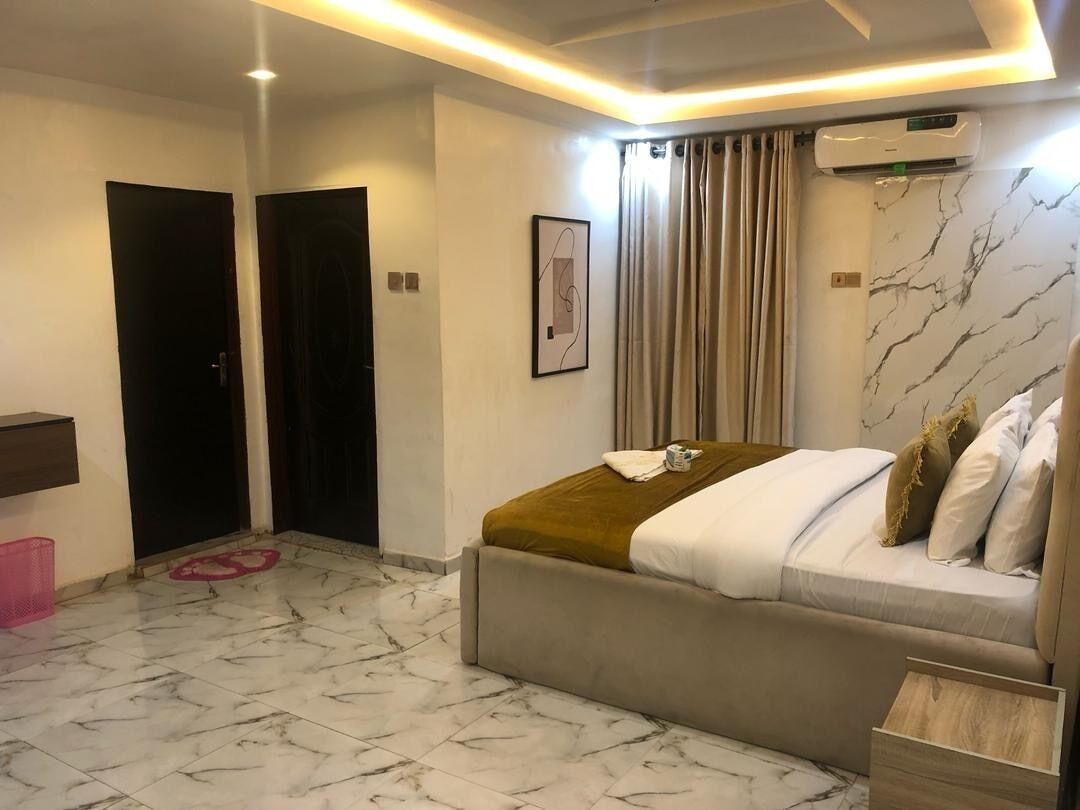 A bedroom with a bed, a wall-mounted air conditioner, a marble floor, and a ceiling light fixture.