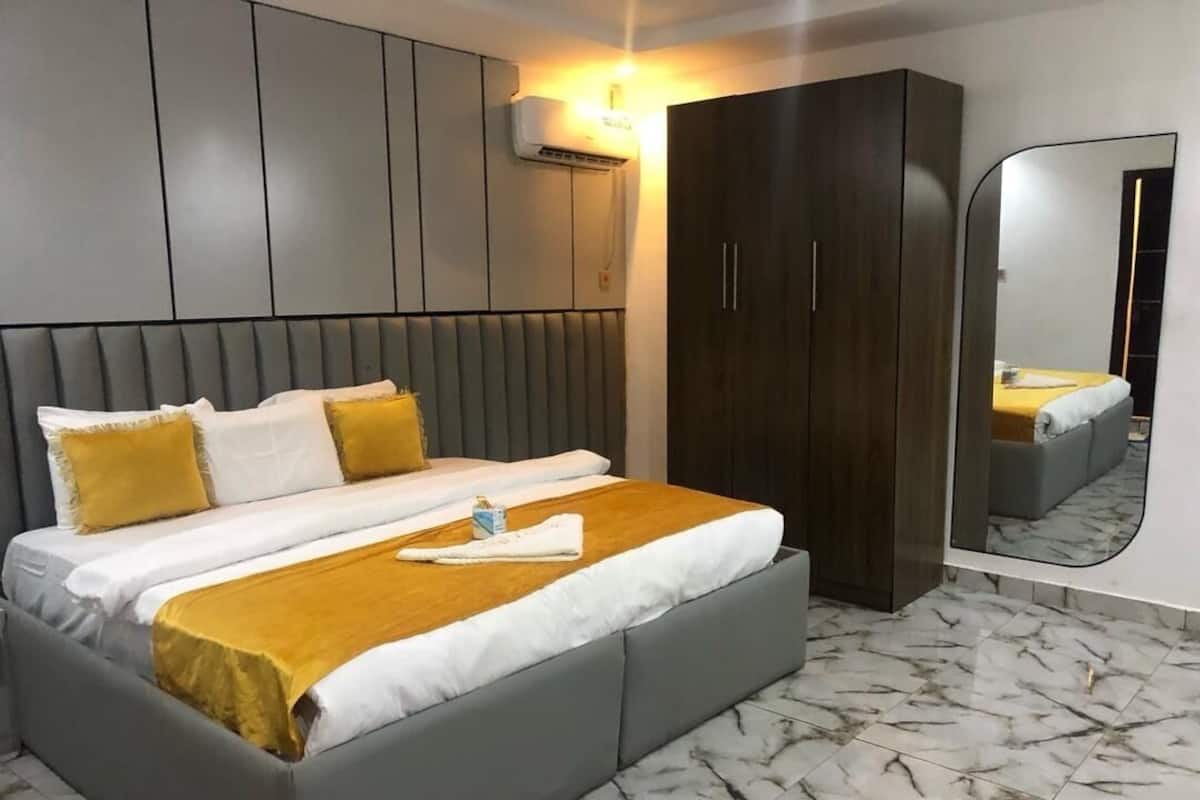 Ein modernes Schlafzimmer mit einem großen Bett, einem Kleiderschrank, einem Spiegel und einem Marmorboden.