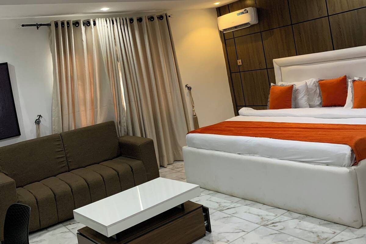 Ein modernes Hotelzimmer mit einem großen Bett, einer Couch, einem kleinen Tisch und einem Fernseher.