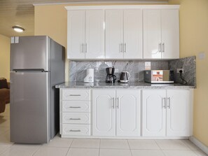 A kitchen with white cabinets, a stainless steel refrigerator, a coffee maker, and a microwave. - Union Hilltop Paradise Villas (Castries)