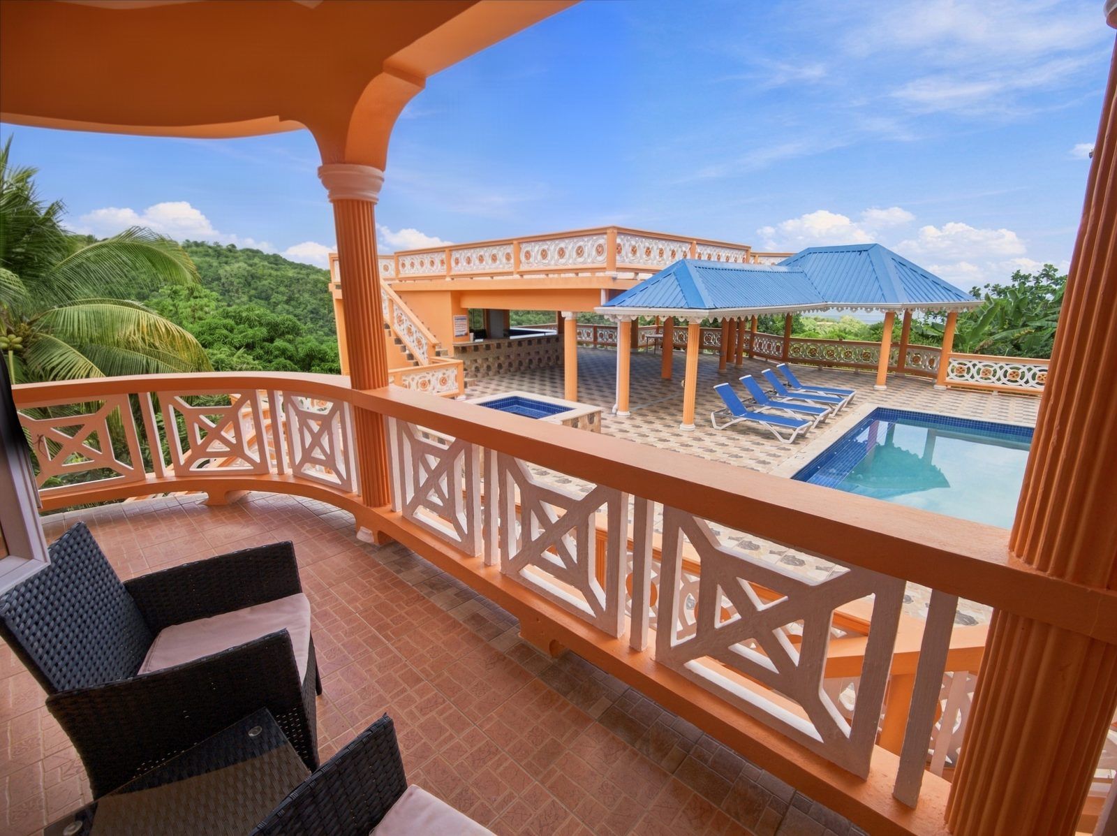 Un balcon avec une piscine, des chaises longues et une vue sur un immeuble dont le toit est bleu.