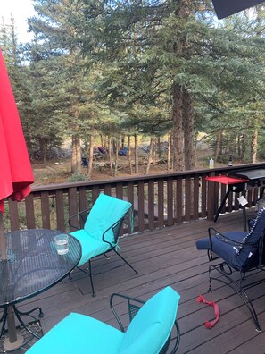 Eine Holzterrasse mit Sitzgelegenheiten und Blick auf einen Wald.