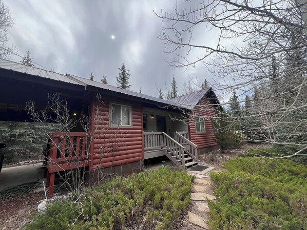 Eine Blockhütte mit einer Holzterrasse und einer Treppe zum Eingang.