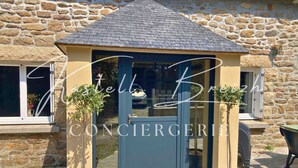 Un bâtiment en pierre avec une porte bleue et deux plantes en pot.