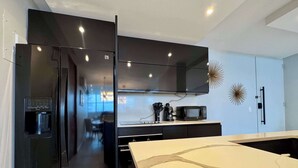 Una cocina moderna con refrigerador integrado, microondas y dispensador de agua.