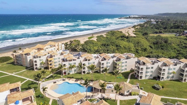 Un hôtel situé en bord de mer, composé de plusieurs bâtiments, doté d’une piscine et offrant une vue sur l’océan.