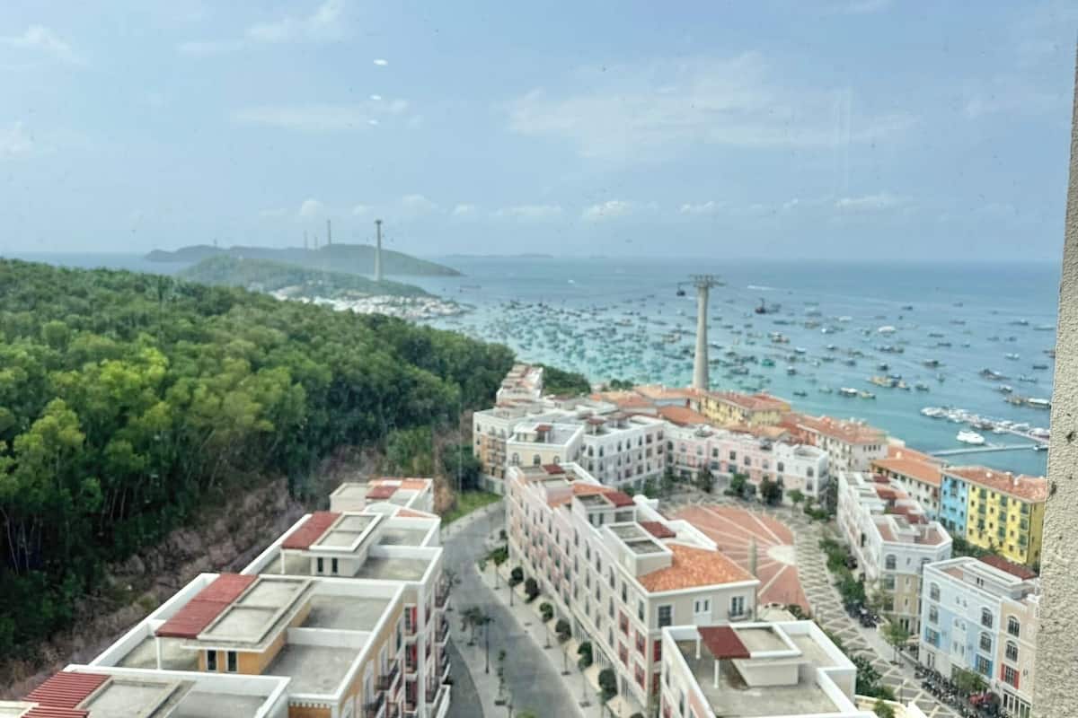 A coastal residential area with apartment buildings, a marina with boats, and a lighthouse in the distance.
