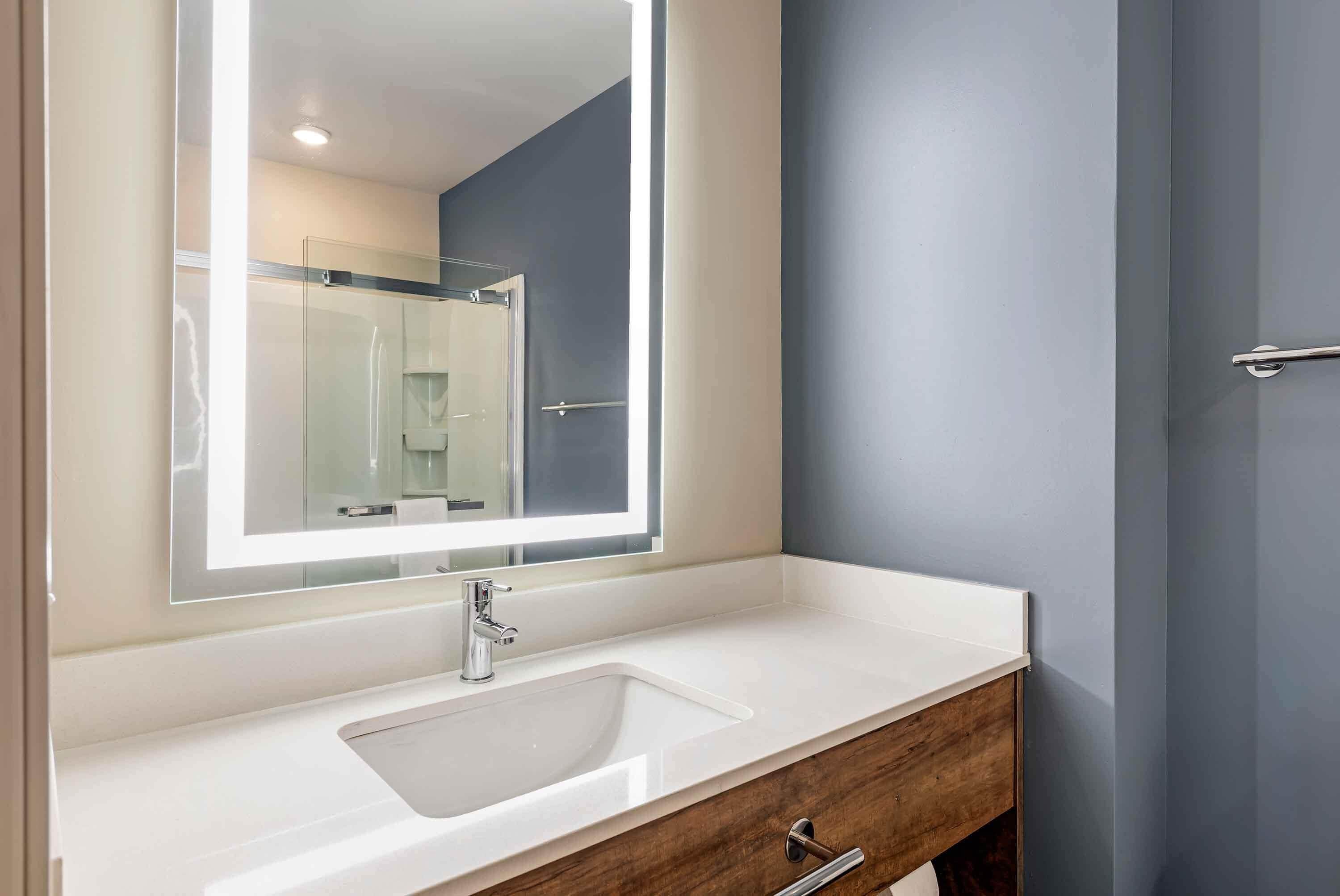 A bathroom with a white sink, a mirror, and a wooden vanity.