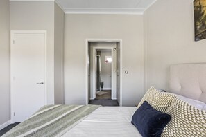 Ett hotellrum med en säng, en dörr och en hall som leder till ett annat rum.