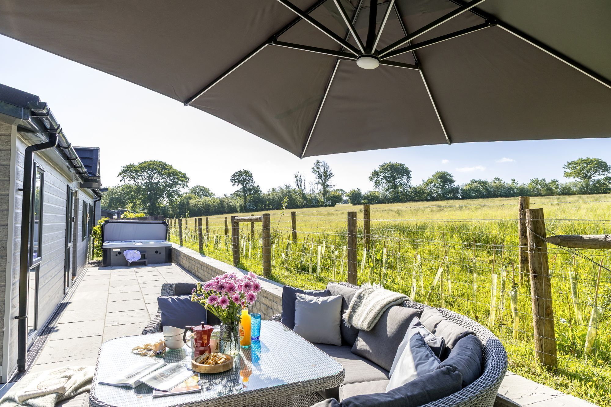 A covered outdoor seating area with a table, cushions, and a grill.