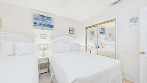 A hotel room with two beds, a large mirror, and artwork on the walls. - Family Fun 181–2BR+Guest Suite–Sleeps 8 (Panama City Beach)