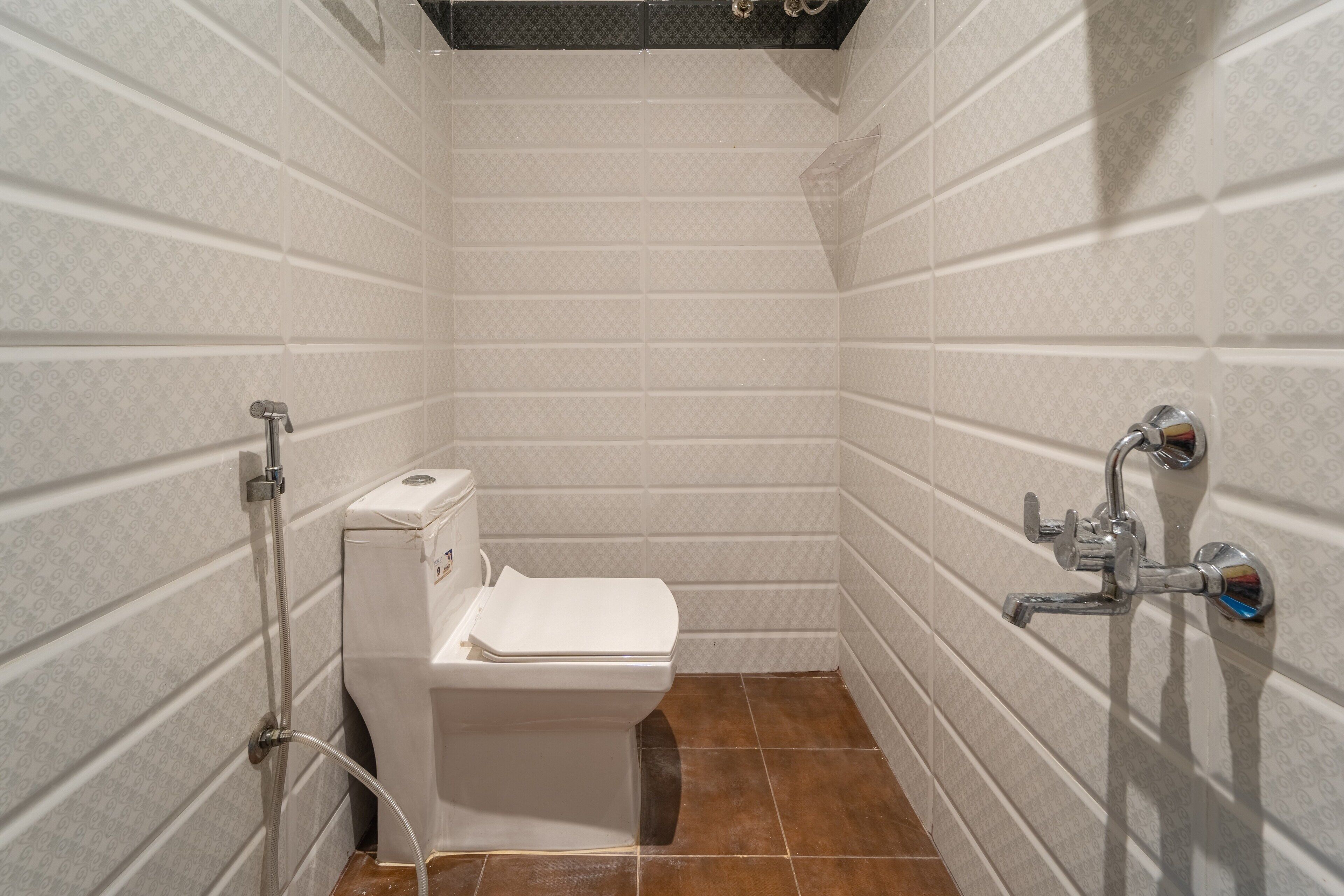 A small, tiled bathroom with a toilet, a shower, and a sink.